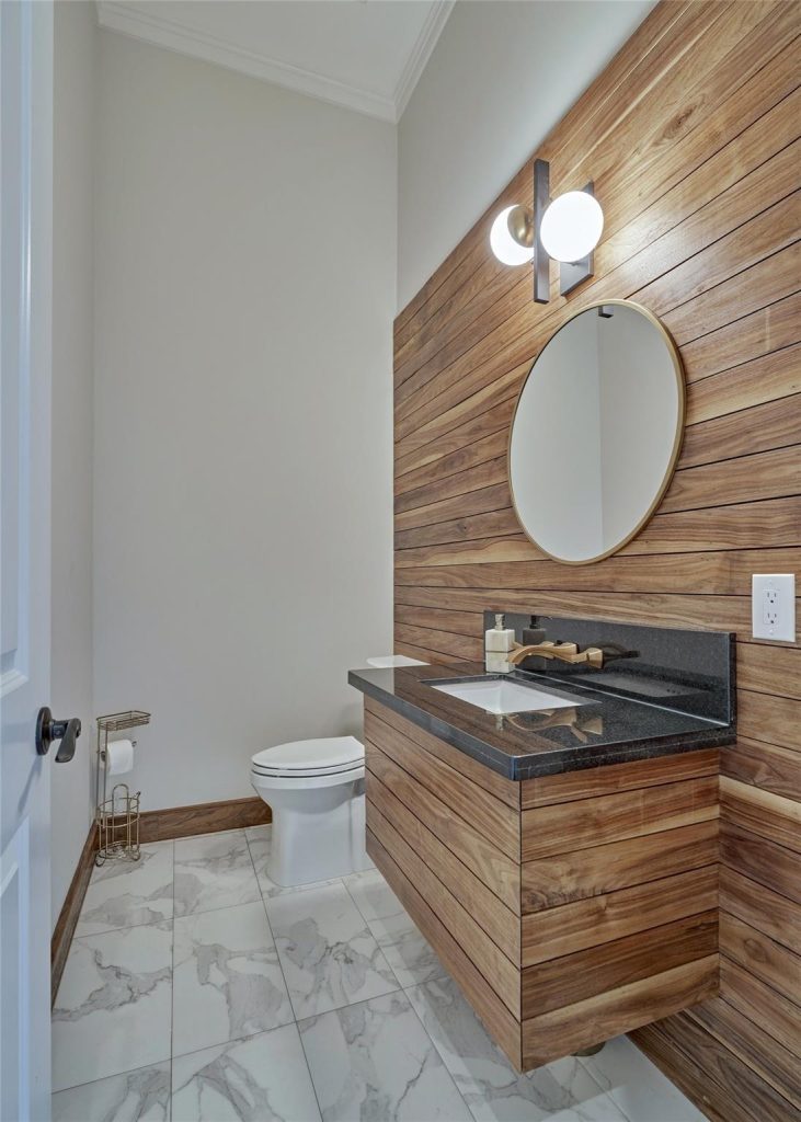 Modern luxury bathroom featuring horizontal wood plank accent wall, floating timber vanity, and marble tiled flooring.