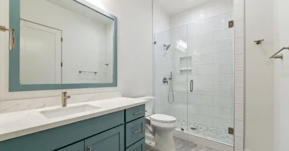 Modern bathroom featuring a teal vanity, marble countertop, matching mirror frame, and a glass-enclosed walk-in shower.