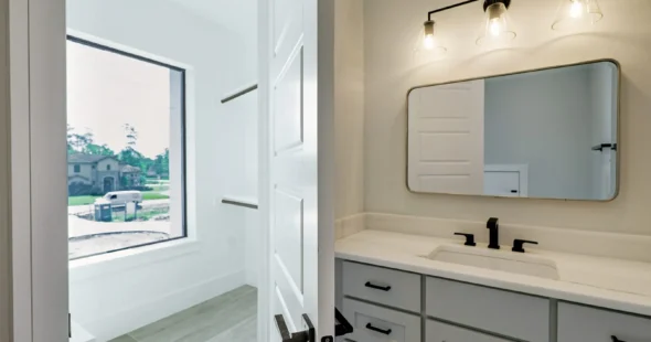 Bright custom bathroom vanity with natural light and gray doors by Iconic Custom Home Builders
