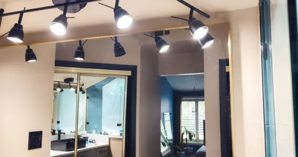 Modern track lighting above bathroom vanity mirror, custom remodel by Iconic Custom Home Builders