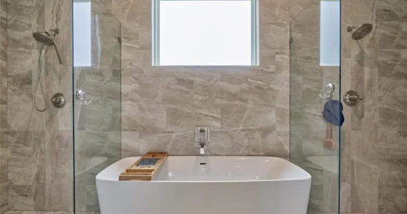Freestanding soaking tub between dual glass showers in luxury bathroom, Iconic Custom Home Builders
